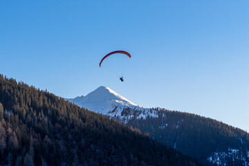 Paraglider above Swiss alps mountain peak infront of blue sky
