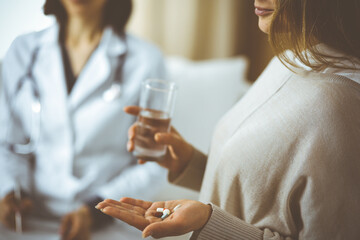 Close-up woman-patient holding pills near her doctor, time to take medications, cure for headache or remedy pain killer drugs. Stay at home concept during Coronavirus pandemic and self isolation