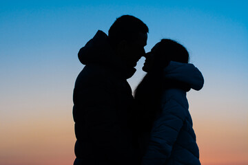 Silhouette of a loving couple in the park on the background of the evening sky, a romantic meeting on Valentine's Day.