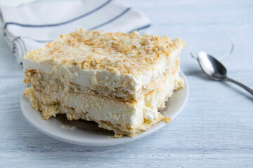 A piece of cake is on a white plate. Napoleon's cake consists of ice cream, layered dough and...