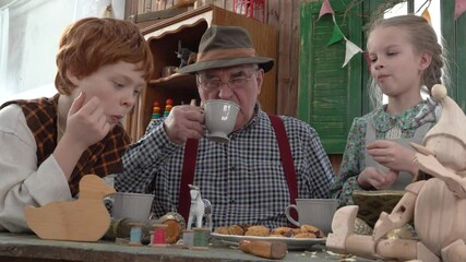 4K. In the carpenter's workshop, Geppetto carpenter Papa Carlo drinks tea with his grandson and granddaughter. Children's fairy tales. A wooden doll with a long nose. The Creation Of Pinocchio.