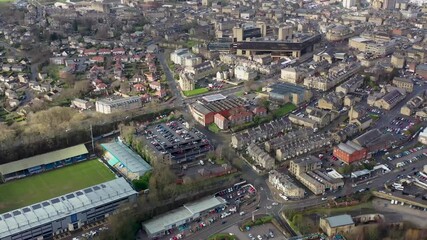 Aerial footage of a football ground in the town of Halifax in West Yorkshire know as Halifax Town Football Club with the drone flying over the town centre to the Piece Hall. - Powered by Adobe