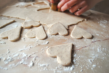 Fototapeta na wymiar The girl prepares cookies in the shape of a heart. Gluten-free rice flour biscuits.