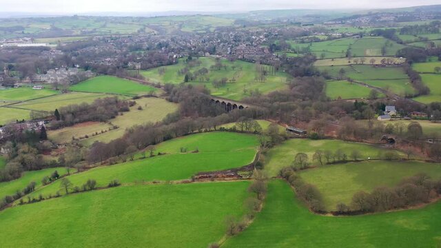 Aerial footage flying across the village of Lightcliffe in Halifax in West Yorkshire in the UK, showing the fields along side a train track viaduct, taken on a cold day in the winter time.