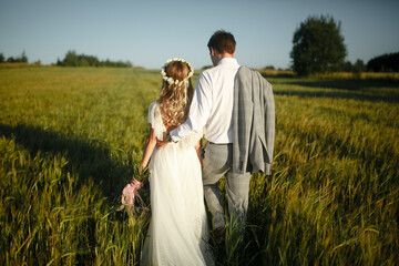 Back view of the groom and the bride in the field.