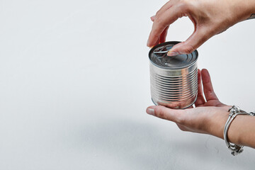 Hand holding a tin with boiled green peas on a white background