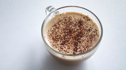 Cappuccino with chocolate in a glass cup on a white background.