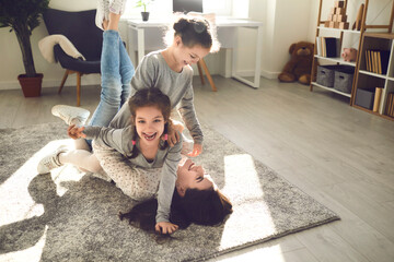 Family enjoying quality time and having fun at home. Young mom and little kids playing on carpet...