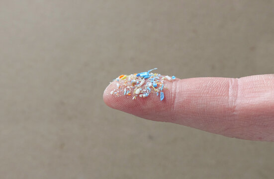 Close up side shot of microplastics on a human finger. Creative concept of water pollution and global warming. Climate change idea. A bunch of plastic rubbish that cannot be recycled.