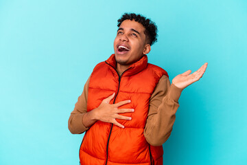 Young african american curly man isolated on blue screaming with rage.