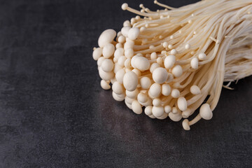 Fresh Enoki mushrooms on black background with selected focus.Enoki, also known as velvet shank, is a species of edible mushroom in the family Physalacriaceae.