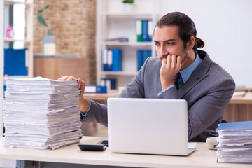 Fototapeta premium Young male employee unhappy with excessive work in the office