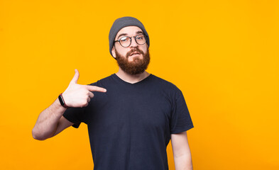 Photo of bearded man pointing at him over yellow background.