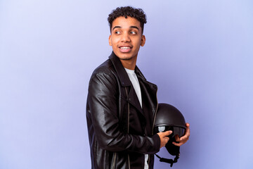 Young african american curly biker man isolated looks aside smiling, cheerful and pleasant.