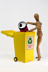 Small wooden mannequin, near the yellow separate collection bin, on a white background