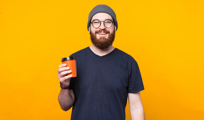 Bearded hipster man holding cup of coffee to go and smiling.
