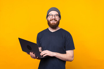 Photo of happy young man looking at camera and using laptop.