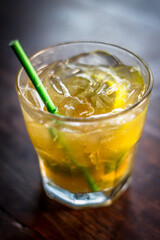 Caipirinha cocktail alcohol drink beverage with lemon slices ice straw and bokeh background on a wooden table