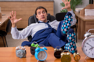 Young male employee sleeping in the office in time management co