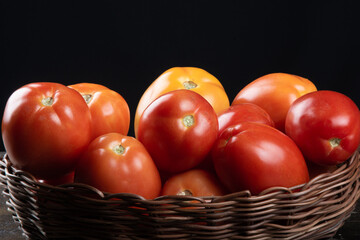 Red tomato in basket with black background