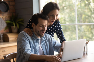 Stunned young Caucasian man and woman use computer shocked by unexpected news or message online....