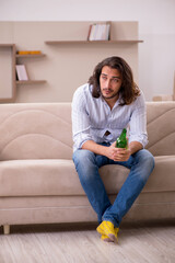 Young man drinking alcohol at home