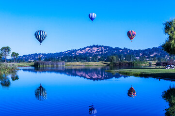 Three Hot Air Balloons Reflected in Four Island Lake