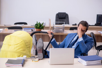 Young male employee looking after new born at workplace