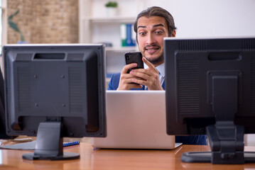 Young male employee in multitasking concept