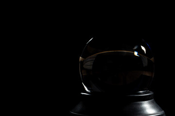Lens ball fortune telling crystal ball in darkness with dramatic lighting. Concept abstract object simple background