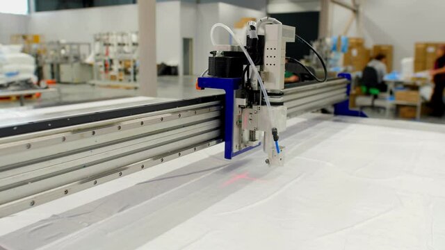 Laser cutting machine operates with sheet of white spunbond