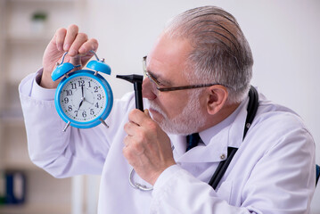 Old male doctor in time management concept