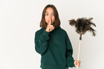Young hispanic woman holding a duster keeping a secret or asking for silence.