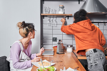 Fototapeta na wymiar Friends enjoying and preparing meal in their kitchen