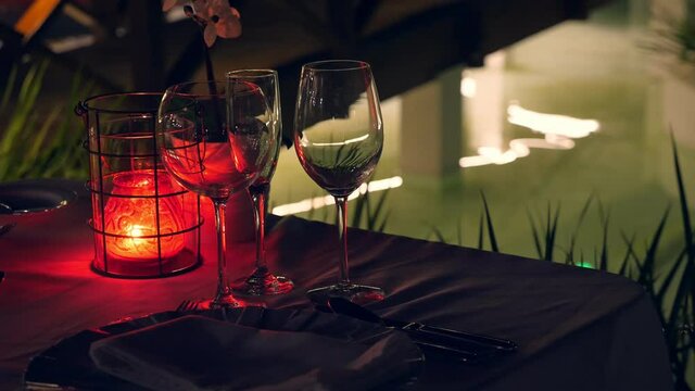 Romantic evening setting wine glasses and candles near swimming pool