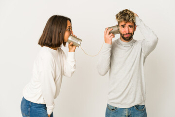 Young hispanic friends talking through a tin can system being shocked, she has remembered important...