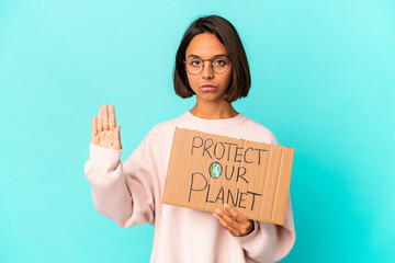 Fototapeta na wymiar Young hispanic mixed race woman holding a protect our planet cardboard standing with outstretched hand showing stop sign, preventing you.