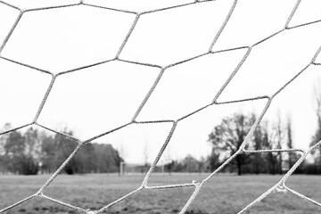 Close-up of a football net in an abandoned field in a Milan park, Italy. Muddy field in the...
