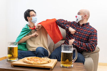 On time of covid-19 two friends celebrate the victory of Italy with masks and with pizza and beer