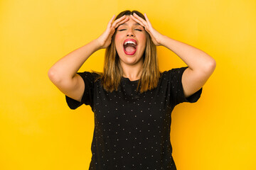 Young indian woman isolated on yellow background laughs joyfully keeping hands on head. Happiness concept.