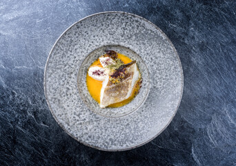 Modern style traditional sauteed skrei cod fish filet with skin with creme fraiche quenelles and...