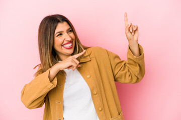Young indian woman isolated on pink background dancing and having fun.