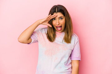 Young indian woman isolated on pink background shouts loud, keeps eyes opened and hands tense.