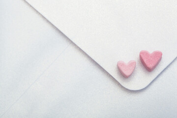 light mother-of-pearl paper craft envelope with two hearts from marshmallow isolated on pink...