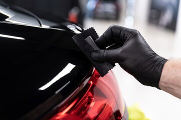 Car detailing studio worker applying ceramic coating on car varnish