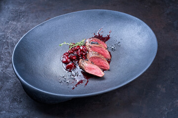 Modern style traditional wild hare back filet braised with wild berries and cherry relish souse served as close-up on Nordic design plate with copy space