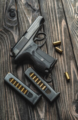 Pistol and cartridges for it on a wooden background. A short-barreled weapon for self-defense