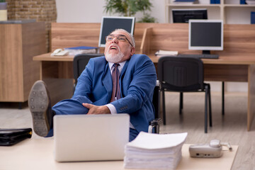 Old businessman employee in wheel-chair working in the office