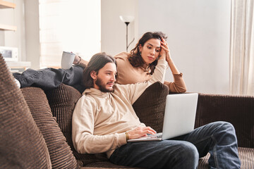 Woman laying at the sofa and looking at the laptop screen