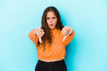 Young caucasian curly hair woman isolated showing thumb down and expressing dislike.
